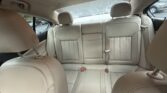 Rear interior of a beige leather car showing back seats, headrests, and visible seat belts.