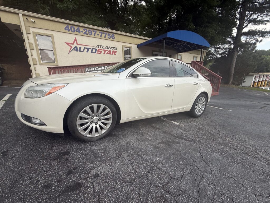 White sedan parked in a lot in front of a beige building with a blue curved awning and Atlanta AutoStar sign visible