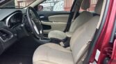 Front interior of a red car with beige cloth seats, steering wheel, and center console gear shifter visible.