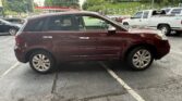 Side view of a maroon SUV parked in a parking lot with white line markings and other vehicles in the background.