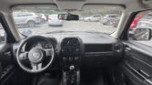 View from the back seat of a Jeep: front dashboard, steering wheel, center console, and rearview mirror with a parking lot of cars outside the windshield.