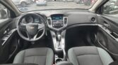 Inside a Chevrolet car’s front cabin, view from the center area of the dashboard facing the windshield and parked cars ahead.
