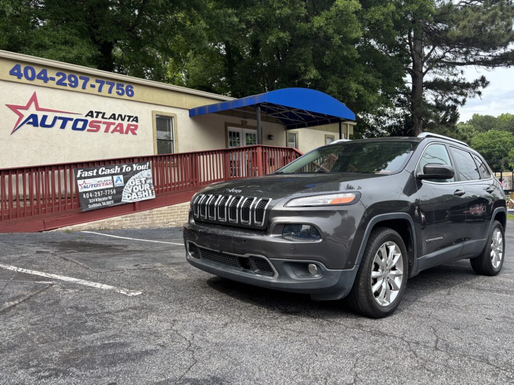 Front of Atlanta Auto Star dealership with a blue awning, red railing, and a gray SUV parked in the lot beside a bannered storefront.