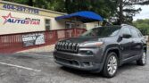 Front of Atlanta Auto Star dealership with a blue awning, red railing, and a gray SUV parked in the lot beside a bannered storefront.