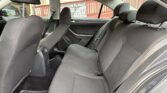 Rear seats of a dark fabric sedan with headrests and seatbelts; outside window shows a sign reading 'Get Your Cash'.