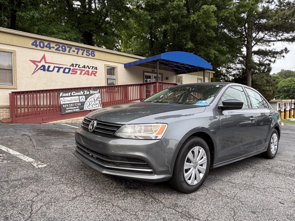 Gray Volkswagen sedan parked in a lot outside Atlanta Auto Star dealership, blue awning visible above the entrance.