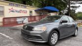 Gray Volkswagen sedan parked in a lot outside Atlanta Auto Star dealership, blue awning visible above the entrance.