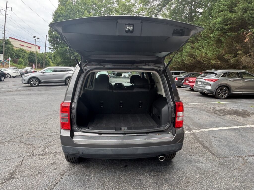 Rear view of a gray SUV with the hatch open, showing an empty cargo area in a parking lot.