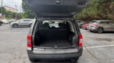 Rear view of a gray SUV with the hatch open, showing an empty cargo area in a parking lot.