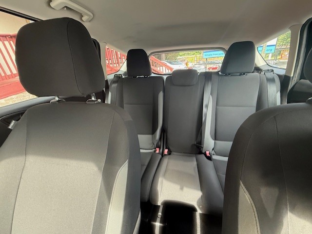 Interior of a gray, three-row car showing front seats and two rear rows with headrests and visible seat belts.