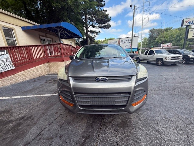 Front view of a gray Ford SUV parked in a lot near a building with a red railing and blue awning.
