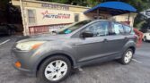 Grey compact SUV parked in front of Atlanta AutoStar dealership building with blue awning and signboard showing the phone number 404-297-7756.