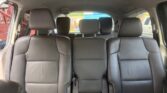 Interior of a black leather minivan showing three rows of seats, with two captain's chairs in the middle row and a center aisle view to the back.
