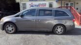 Gray minivan parked in front of a car dealership building with a blue sign reading 'Atlanta Auto Star' and a blue awning above the entrance.