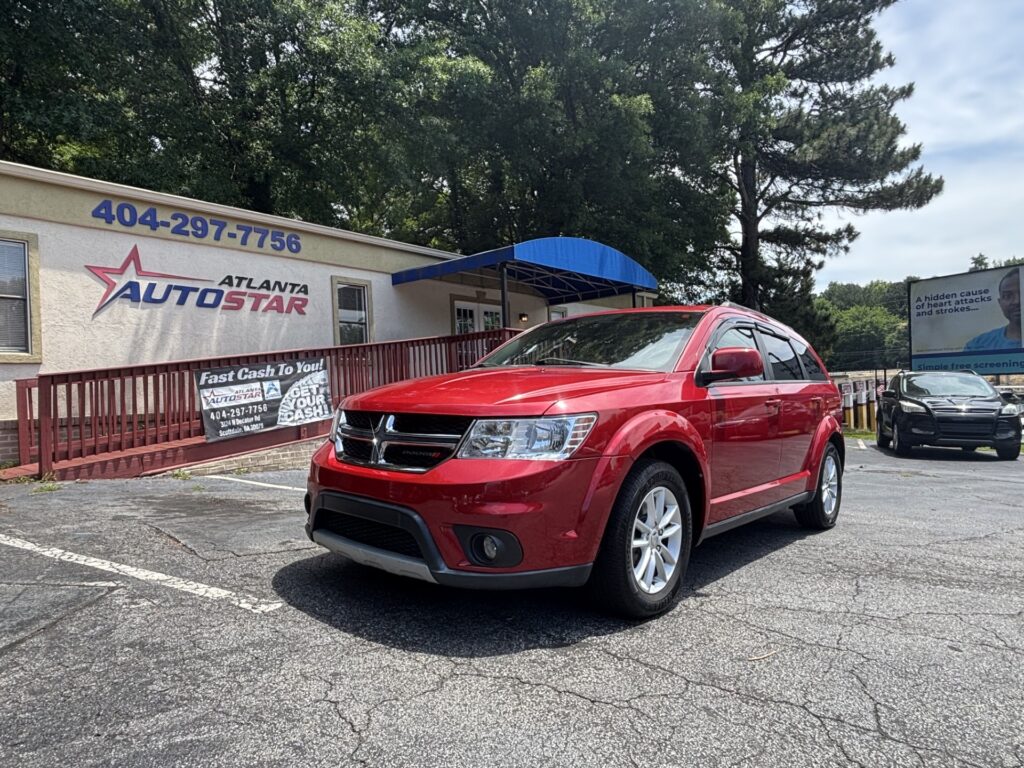 Red Dodge SUV parked in front of the Atlanta Auto Star dealership, under a blue awning with the sign above.