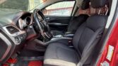 Interior of a red SUV showing the front seats, steering wheel with a cover, and bold red floor mats; a 'Fast Cash To You' sign is visible through the window outside.