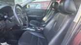 Interior of a car with black leather seats and white contrast stitching, steering wheel, and center console visible from the driver’s side door edge.