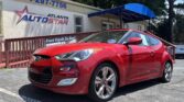 Red Hyundai sports car parked in front of Atlanta Auto Star dealership with a blue awning and banner nearby