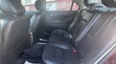 Rear seat area of a car with black leather upholstery and three headrests, viewed from the back seat window side.