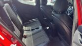 Red car interior rear seating area with black fabric seats, center console cupholders, and front seats visible from the open rear door.