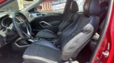 Front interior of a red car with black leather seats, steering wheel, and center console visible. A 'Fast Cash' sign is seen outside the window.