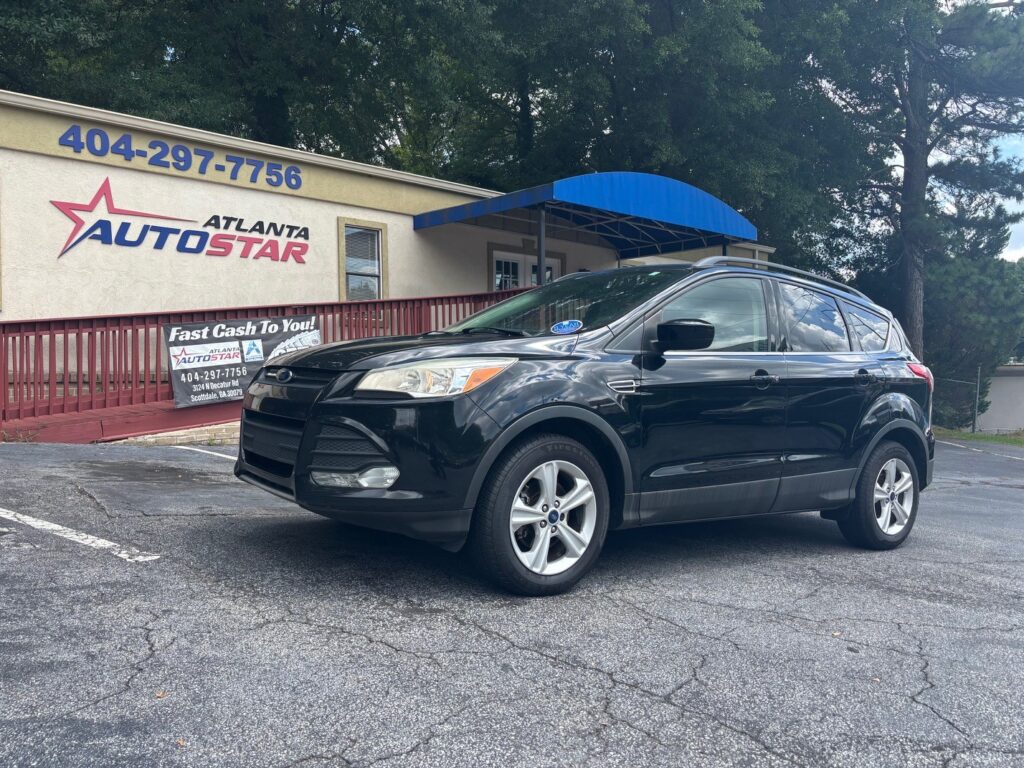 Black Ford SUV parked in front of Atlanta AutoStar dealership, blue canopy overhead and business signs visible on the building.