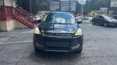 Front view of a black Ford SUV parked in a lot, with a red railing building on the left and billboards in the background. Was this helpful? Or should I tailor it to a specific page?
